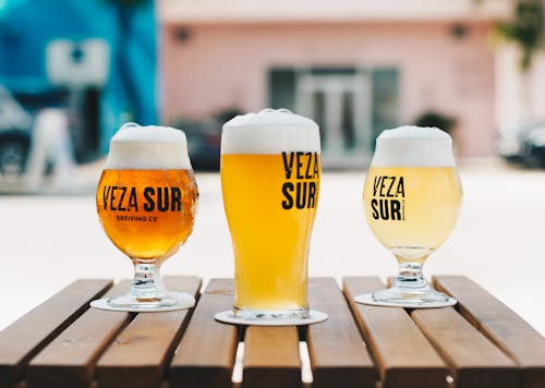 Fotografia De Profundidade De Campo De Três Copos De Cerveja Em Uma Mesa De Paletes De Madeira