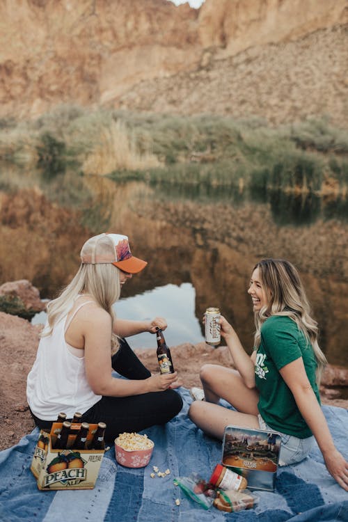 Woman in Green Crew-neck T-shirt Sitting Beside Woman in White Top on Picnic