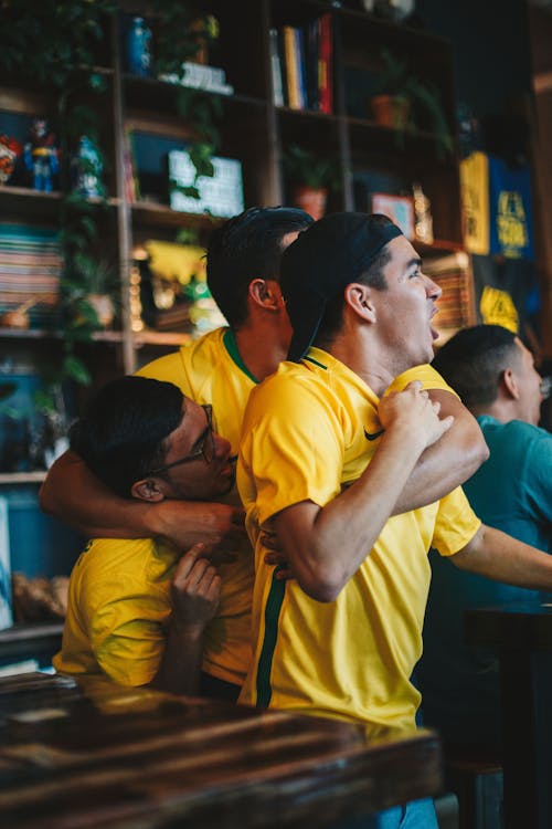 Free Three Men Wearing Yellow Shirt Embracing Each Other Stock Photo