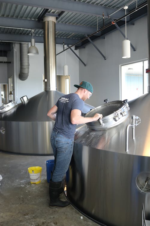 Man Wearing Gray T-shirt and Blue Jeans Looking at Stainless Steel Container