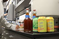 柜台上摆着各种精酿啤酒的瓶子和罐子，背景里有一名男子的字样