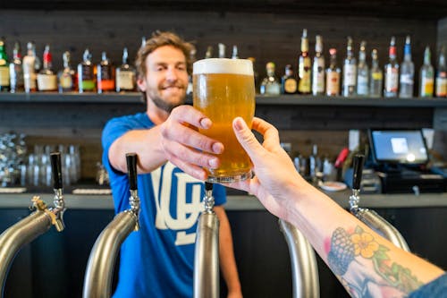 Free Man Handing a Person a Glass of Beer Stock Photo