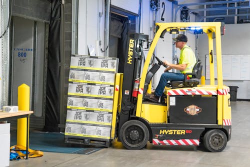 Man Riding a Yellow Forklift lifting Boxes