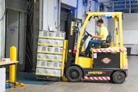 Man Riding a Yellow Forklift lifting Boxes