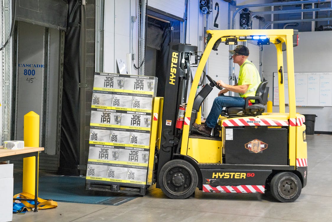 Free Man Riding a Yellow Forklift lifting Boxes Stock Photo