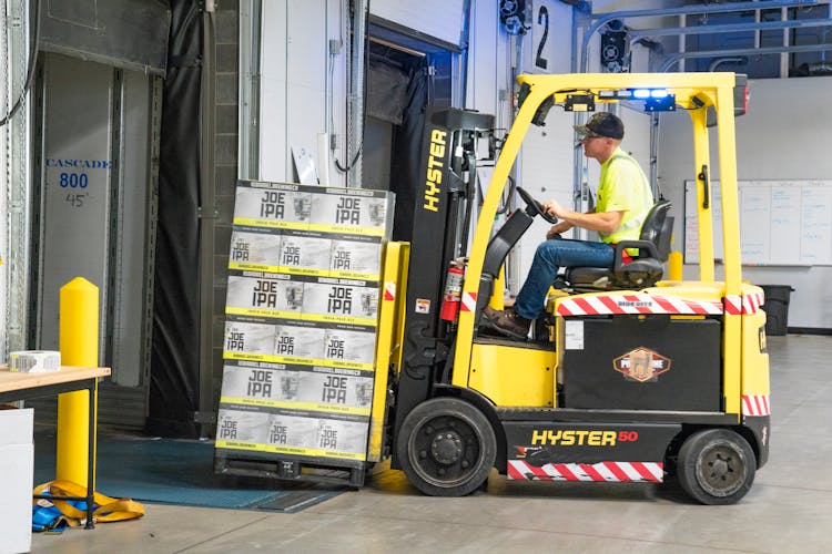 Man Riding A Yellow Forklift Lifting Boxes