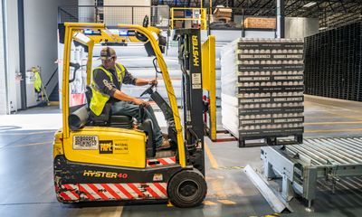 Forklift operator moving pallets in warehouse