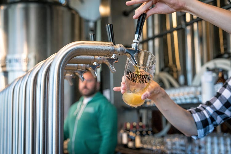 Person Filling Drinking Glass With Beer On Tap