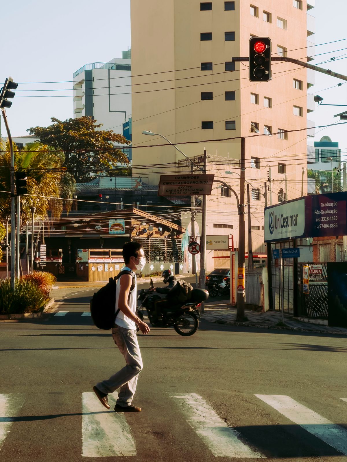 Trabajador con mochila cruza una calle durante su trayecto al trabajo