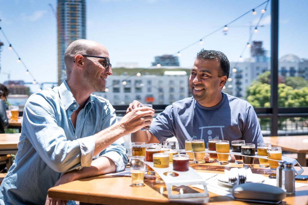 Friends sharing a tasting flight of beers outside the taproom
