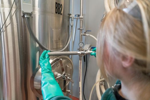 Person Wearing Gloves While Fixing Distillation Tank