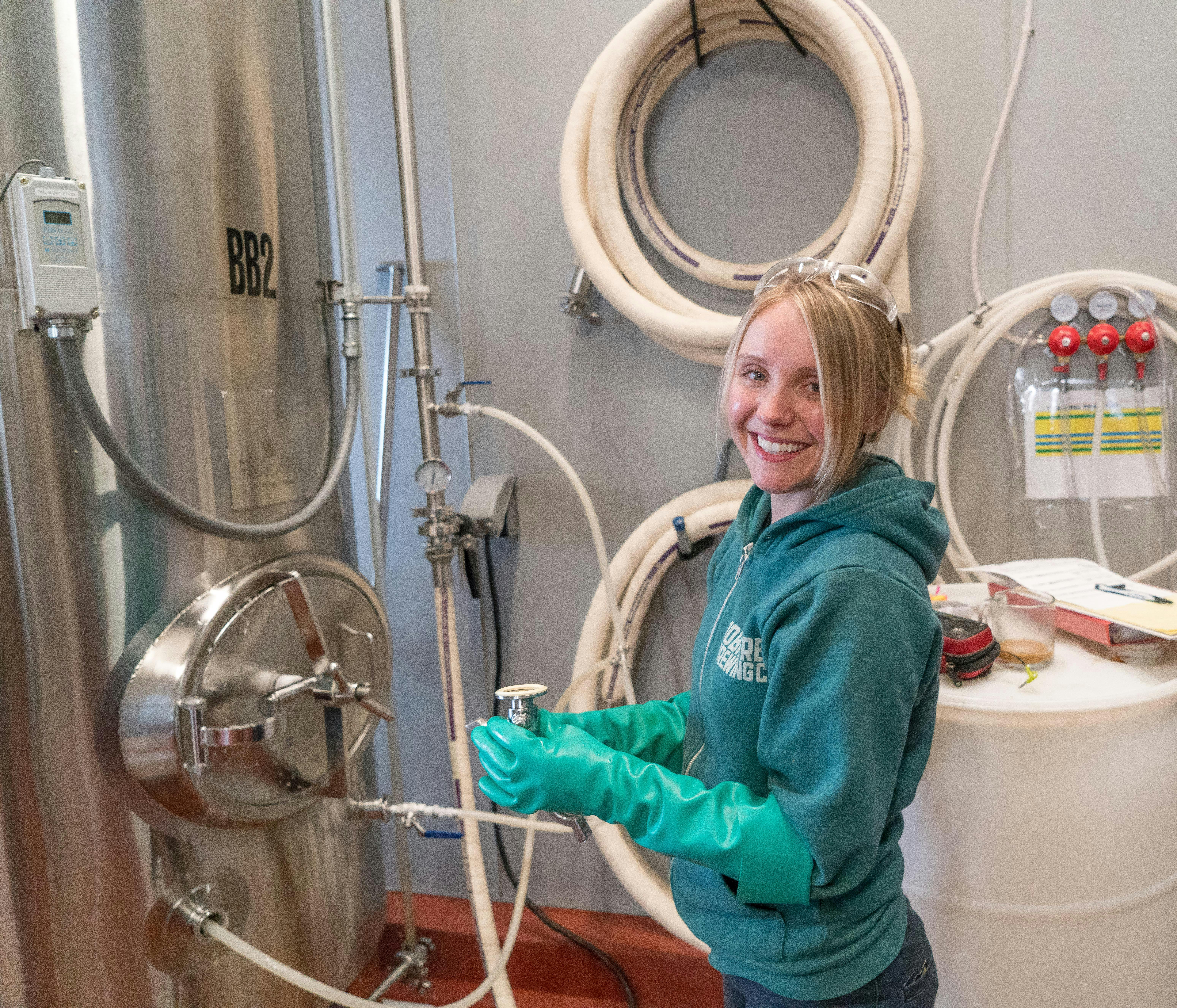 Foto de mulher cientista vendo o compartimento onde está sendo feita a cerveja