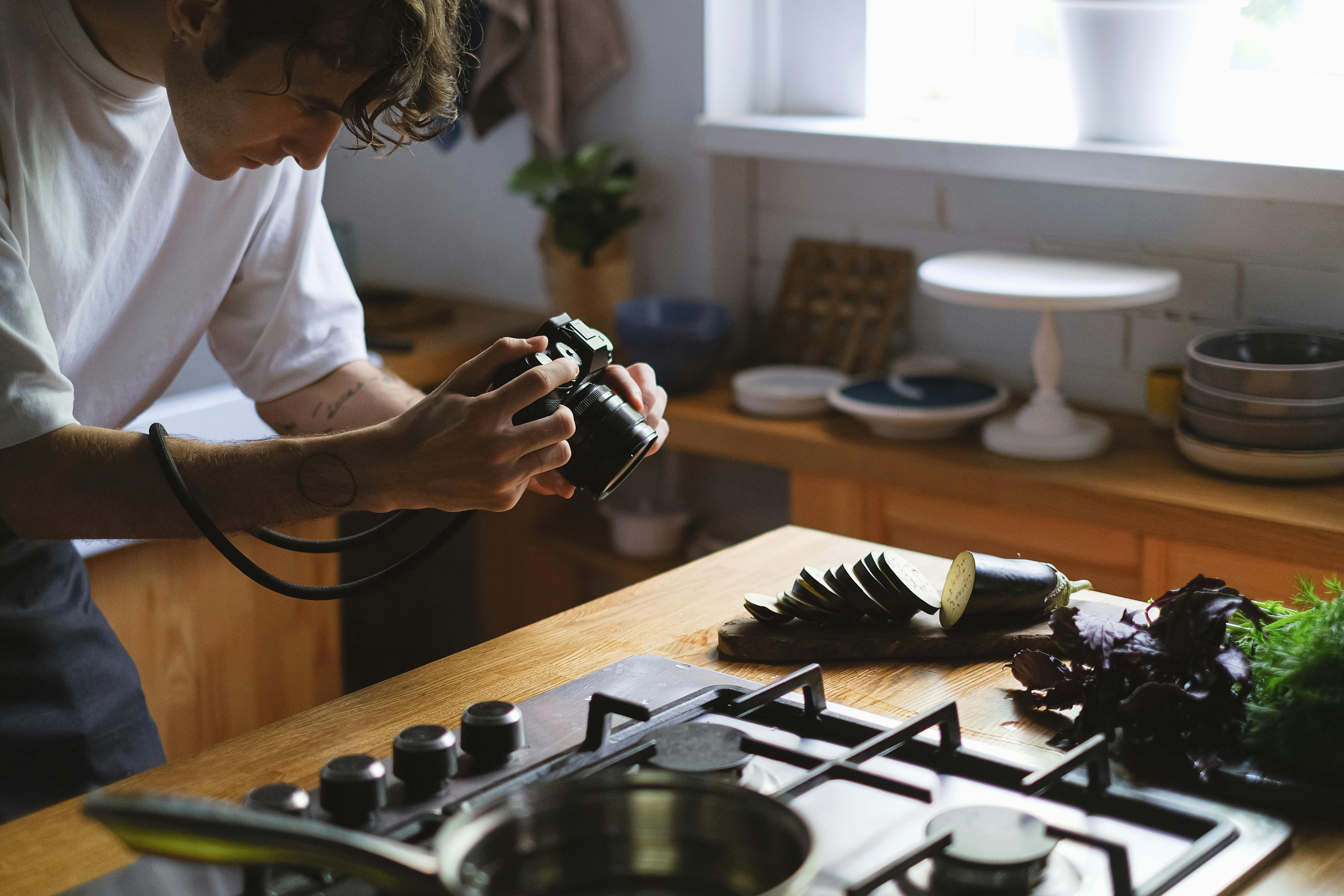 A photographer captures a sliced eggplant and greens in a stylish kitchen environment.