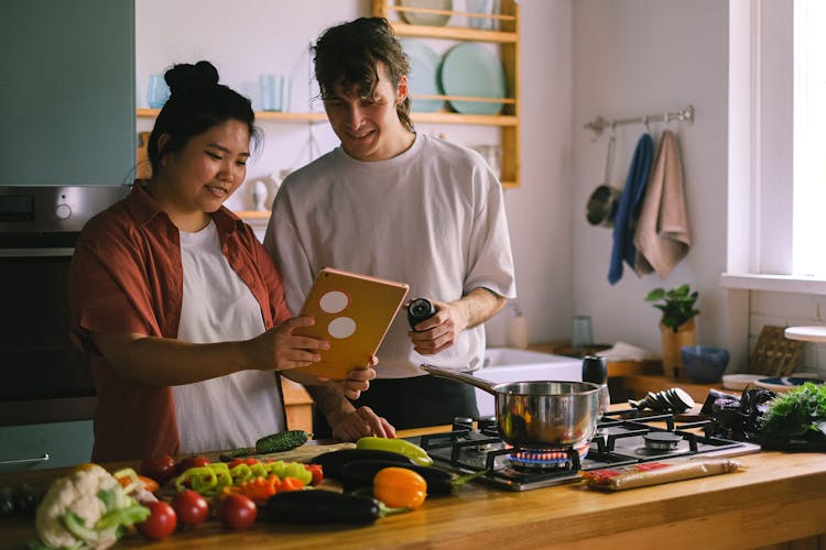 Couple Cooking And Looking At A Tablet In A Kitchen