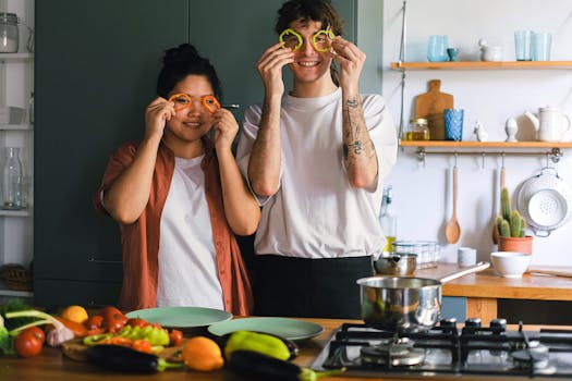 Two adults having fun with vegetables while cooking in a modern kitchen.
