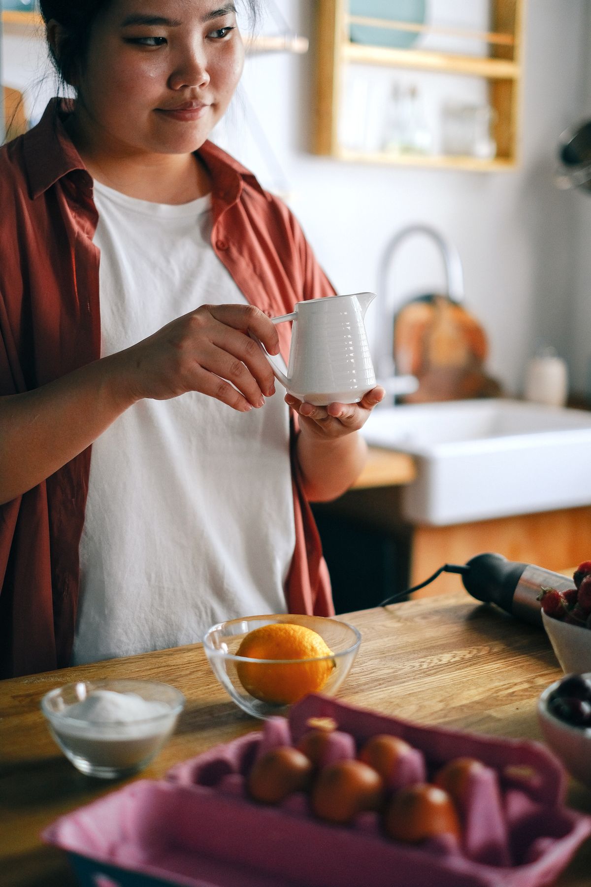 Woman preparing ingredients at a kitchen counter in a warm home kitchen