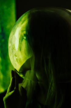 Artistic close-up portrait of a woman with green lighting and reflective surface.