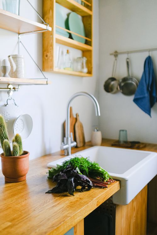 Free Bright kitchen interior featuring fresh herbs on a wooden countertop next to a farmhouse sink. Stock Photo