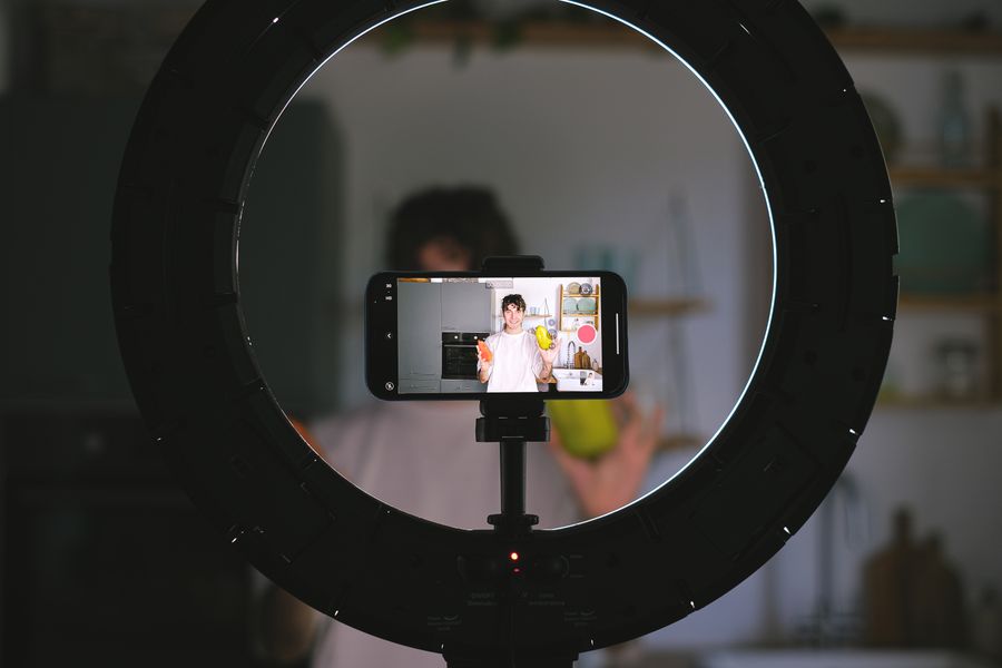 Food content creator filming a video with a smartphone and ring light