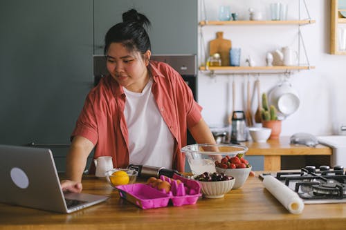 Free A Person Using a Laptop While in the Kitchen Stock Photo