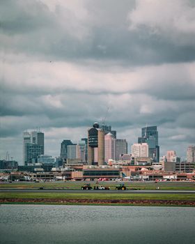 Scenic view of Boston skyline under a dramatic cloudy sky, featuring waterfront and cityscape.