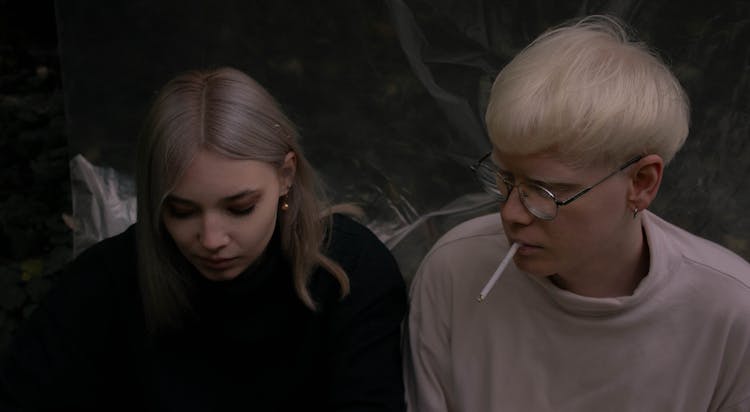 Blond Man And Woman Sitting And Smoking A Cigarette