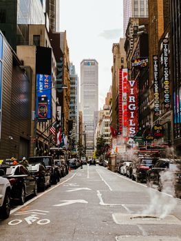 Discover the bustling atmosphere of a New York City street lined with cars and iconic signage, framed by skyscrapers.