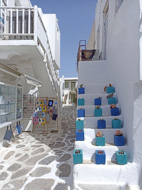 Free Picturesque alleyway in Greece with blue potted plants on white stairs, showcasing Greek architecture. Stock Photo