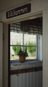Charming entrance with a welcoming sign and window view of a plant. — photo by Tushar Mahajan