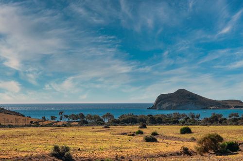 Free Beautiful coastal landscape showcasing a rocky mountain, clear blue sea, and expansive skies. Stock Photo