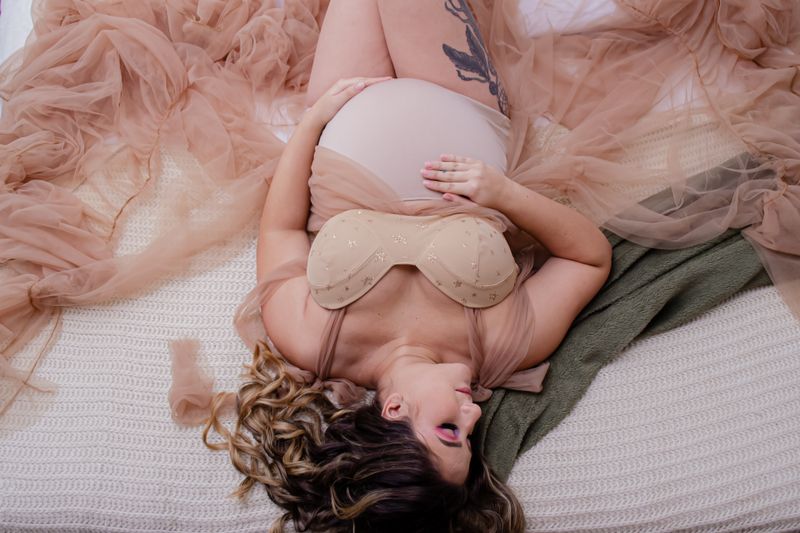 A serene and elegant portrait of a pregnant woman lying down, highlighting her beauty and anticipation.
