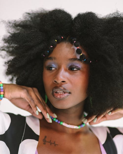 Portrait of a Woman with Afro Hairstyle and Bead Necklace against White Background