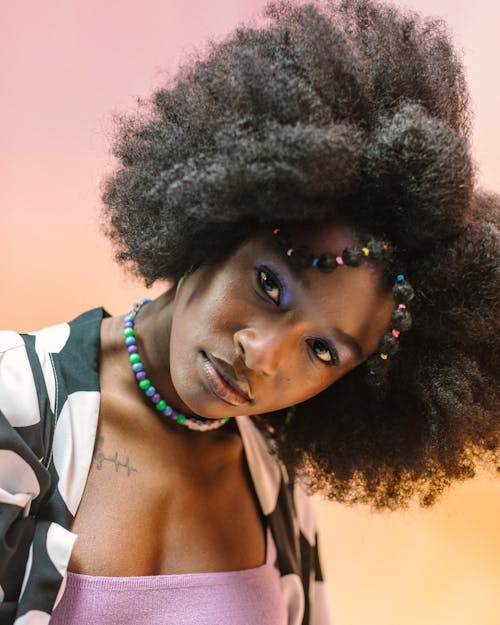 Portrait of a Woman with Afro Hairstyle and Bead Necklace against Pastel Background