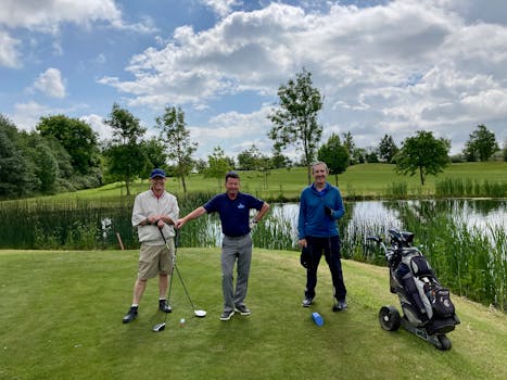 Three golfers smiling on a green Irish course with clear skies and lush surroundings.
