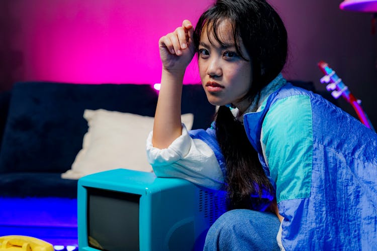 Young Woman Sitting On A Sofa Near A Vintage Television 