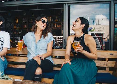 Duas Mulheres Sorridentes Sentadas Em Um Banco De Madeira