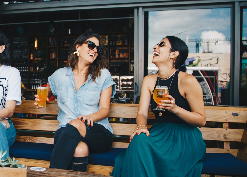 gratis Twee Glimlachende Vrouwen Die Op Houten Bank Zitten Stockfoto