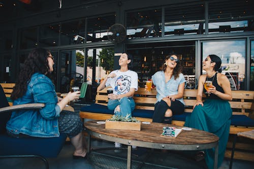 Free Four Women Chatting While Sitting on Bench Stock Photo