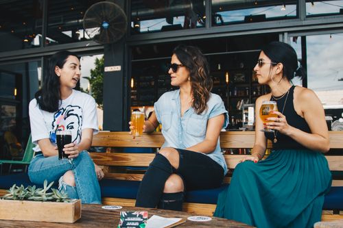 Free A group of women in conversation enjoying drinks at an outdoor bar. Stock Photo
