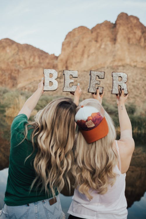 Selective Focus Photography of Two Women Holding Beer Cutout Letters