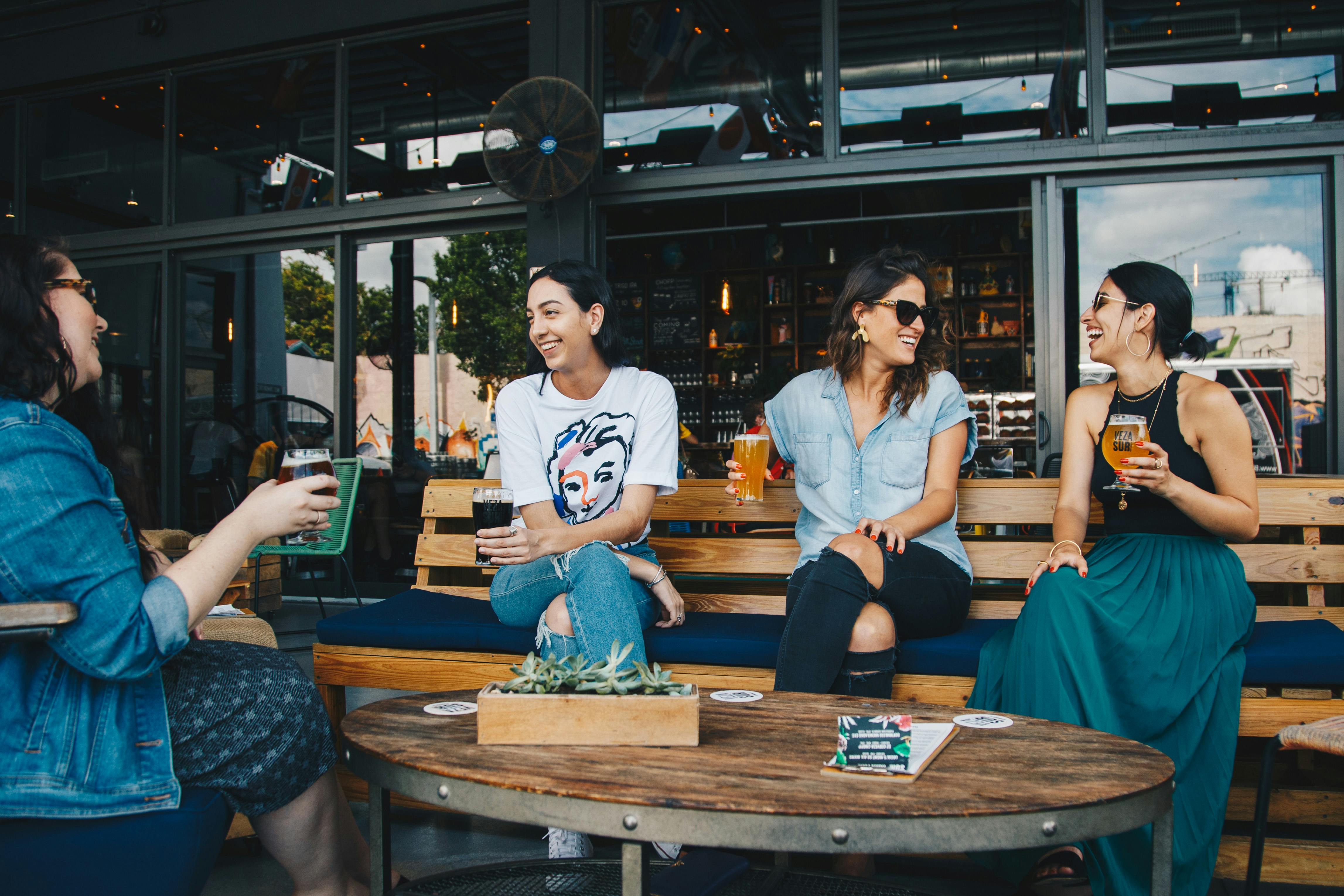 four women sitting on benches outside building