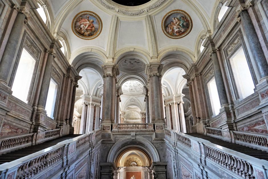 Majestic interior of the Royal Palace of Caserta featuring grand staircases and ornate architecture.