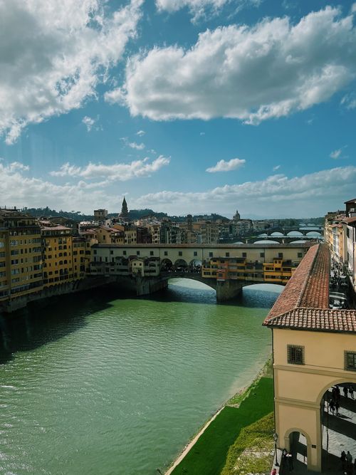 Free A scenic view of Ponte Vecchio spanning the Arno River under a vibrant sky in Florence, Italy. Stock Photo