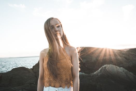 Young woman enjoying a sunny day by the rocky coast of Hol, Norway.