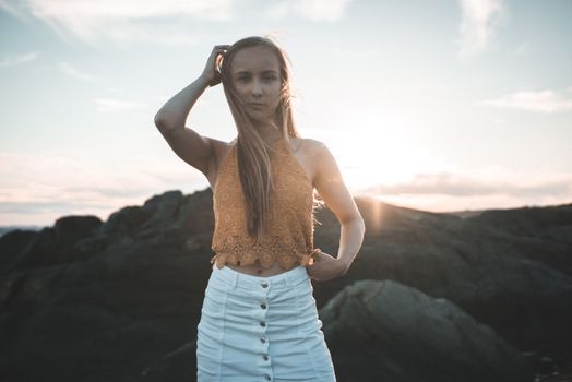 Young woman posing by rocky landscape during sunset in Norway.