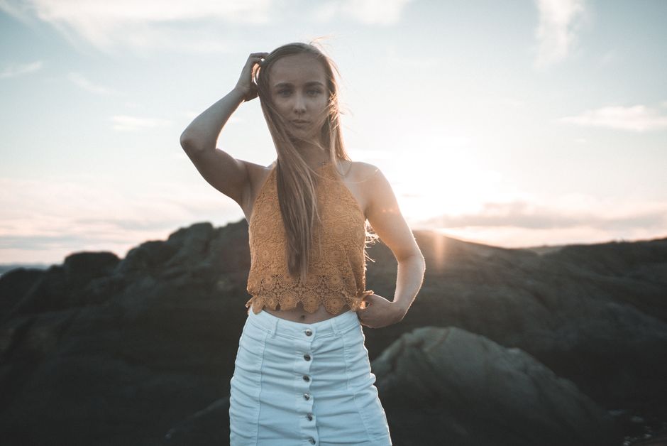 Young woman posing by rocky landscape during sunset in Norway.