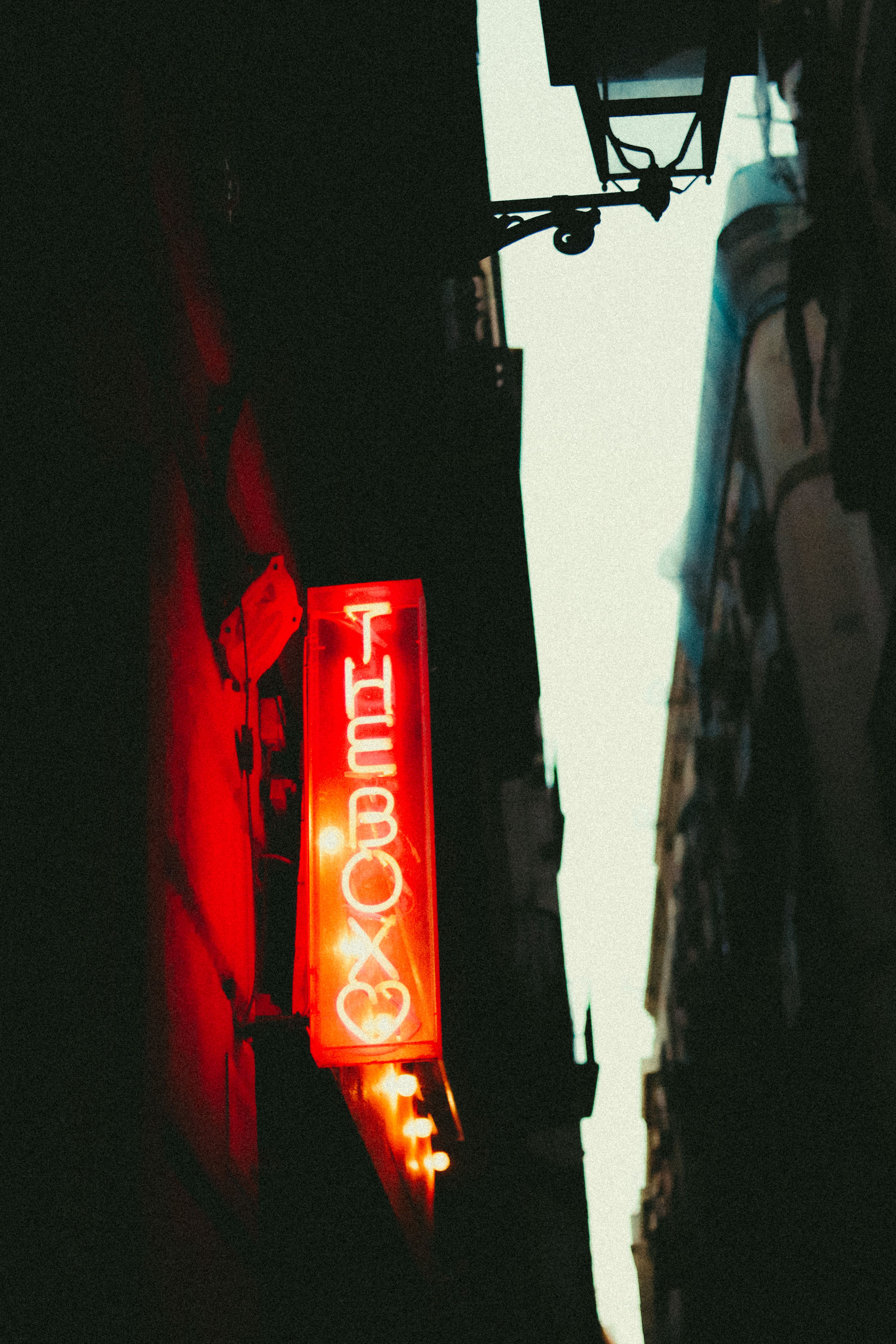 A red neon sign reads 'THE BOX' in a dimly lit urban alleyway, creating a moody atmosphere.