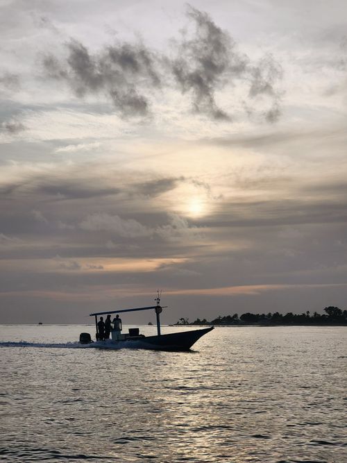 Free A motorboat silhouettes against the stunning sunset skyline over the ocean in Maldives. Stock Photo