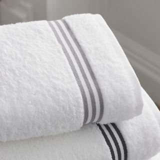 Folded white cotton bath towels with grey stripes, photo by Thomas Cotton on Pexels
