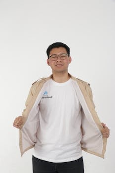 Portrait of a smiling Asian man wearing eyeglasses and a white shirt, revealing his beige jacket.